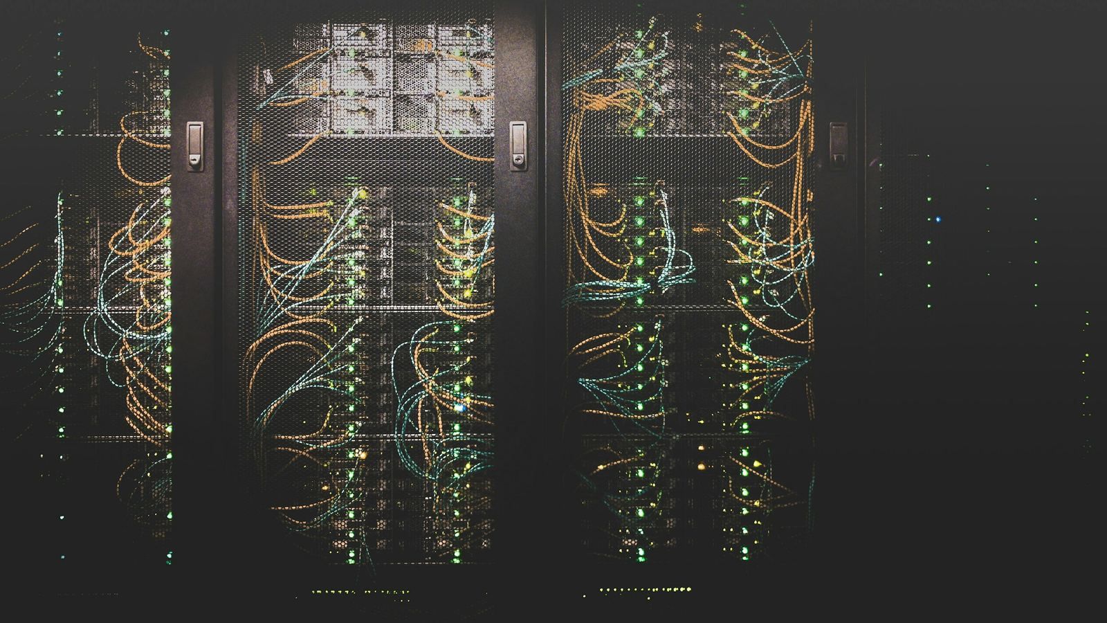 Server racks with cabling and status lights in a dark data centre